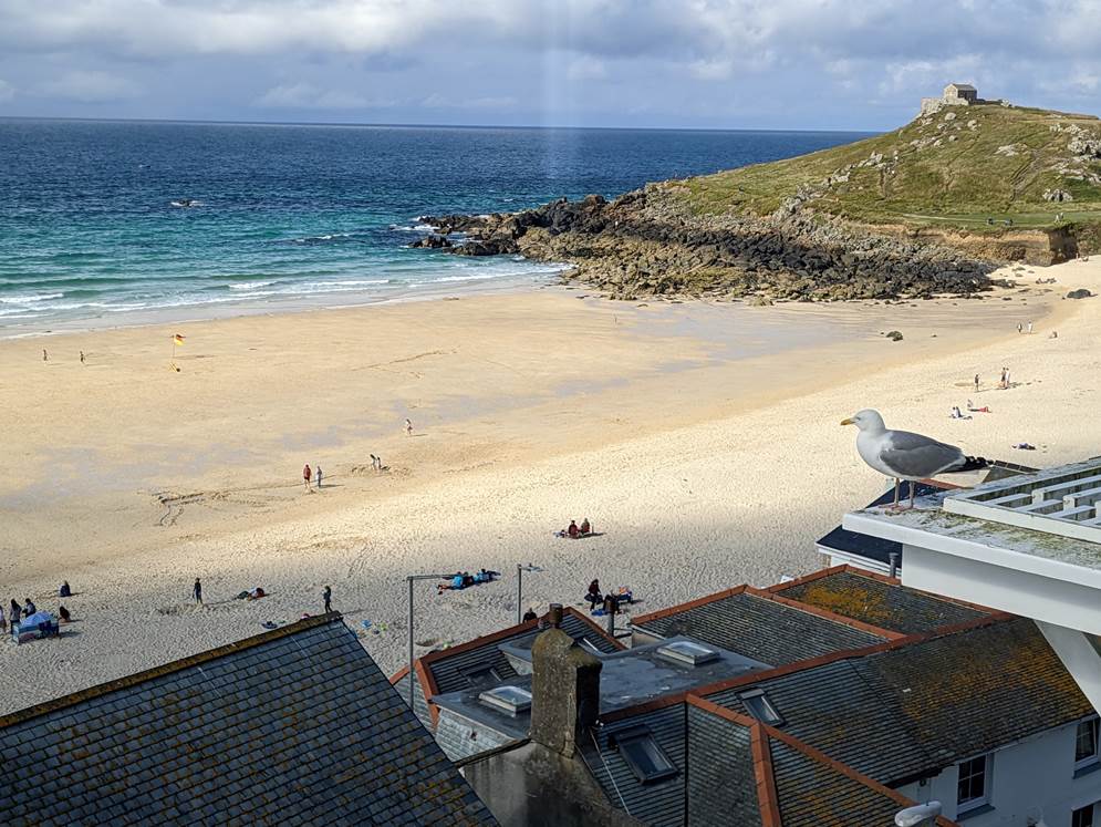 A beach with a group of people and a house

Description automatically generated